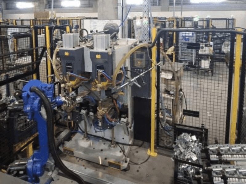 Gerçek fabrika fotoğrafı — tam PRP otomasyon hücresi, robotlar görünür durumda.